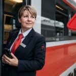 Zamestnankyňa ZSSK stojí pri osobnom vlaku na železničnej stanici počas hromadného prepúšťania v spoločnosti.